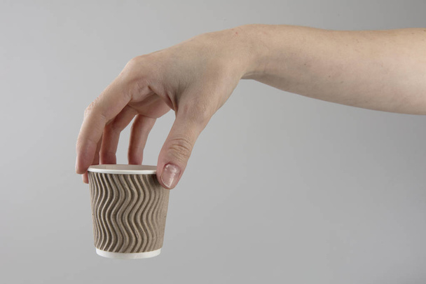 Гофрована чашка для гарячих напоїв тримає жіноча рука
 - Фото, зображення