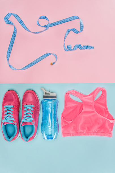 Sports equipment with shoes, measuring tape and sports top isolated on pink and blue - Photo, Image