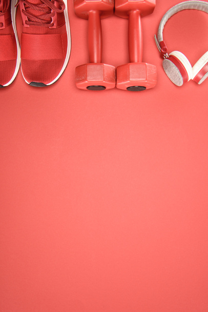 Equipamiento deportivo con zapatos, mancuernas y auriculares aislados en rojo
 - Foto, Imagen