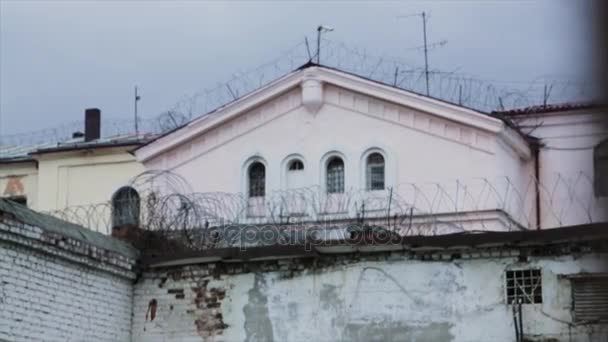 Barbed wire fence attached around prison walls. Historic brick prison wall showing guard tower and coiled barbed wire - Filmmaterial, Video