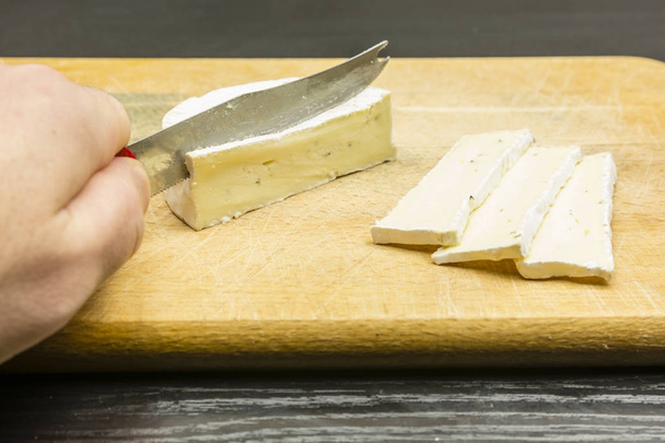 Bir kesme tahtası üzerinde bir bıçak ile kesmek bir lezzetli camembert peyniri. - Fotoğraf, Görsel