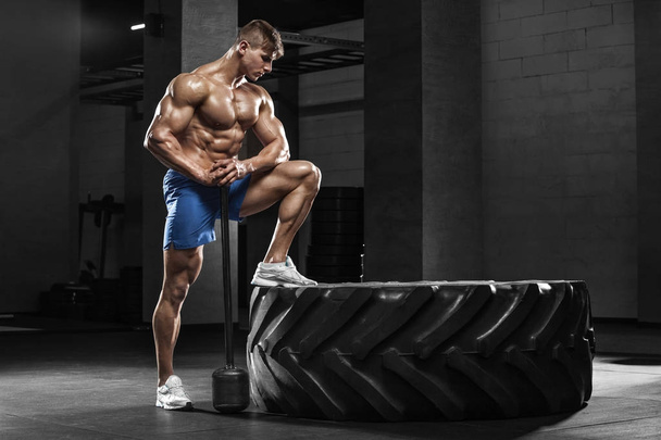 Kaslı adam lastik, güçlü erkek çıplak gövde abs ile spor salonunda egzersiz - Fotoğraf, Görsel