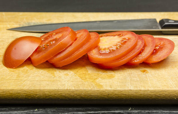 Tomaat met plakjes gesneden op een snijplank. - Foto, afbeelding