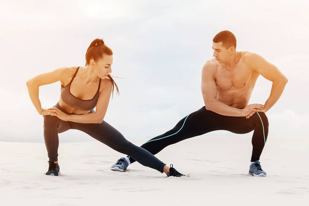 Фитнес-пара делает упражнения на растяжку. Атлетичные мужчина и женщина
 - Фото, изображение