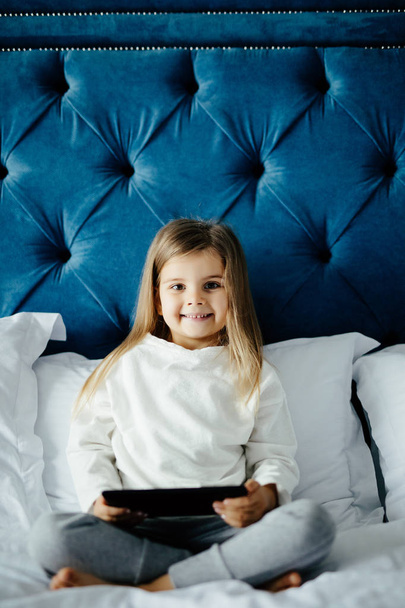 Menina bonito usando um computador tablet em seu quarto em casa
 - Foto, Imagem