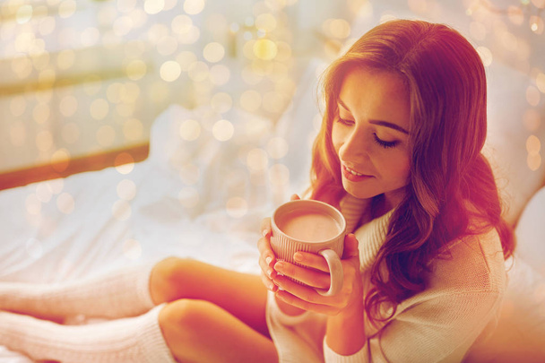 happy woman with cup of cocoa in bed at home - Photo, Image