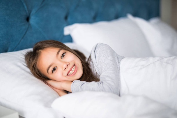 Αξιολάτρευτο κοριτσάκι να ξυπνήσεις επάνω στο κρεβάτι της στο σπίτι - Φωτογραφία, εικόνα