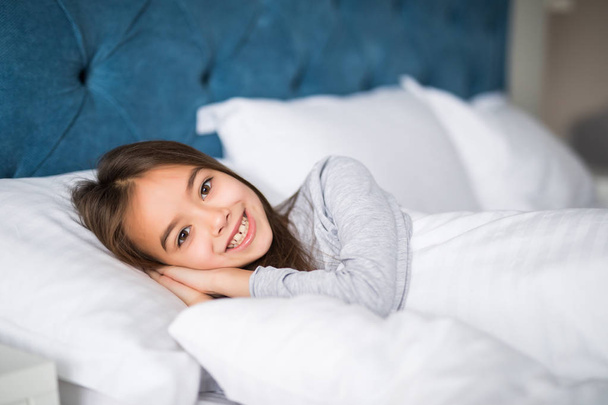 Мила красуня маленька дівчинка лежить в ліжку вдома
 - Фото, зображення
