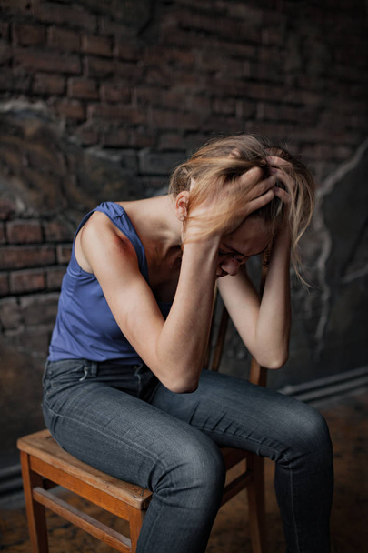 Mulher chorando vítima de violência doméstica e abuso senta-se na cadeira com hematomas e feridas em seu corpo
.  - Foto, Imagem