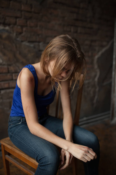 Λυπημένη γυναίκα θύμα ενδοοικογενειακής βίας και κακοποίησης κάθεται σε καρέκλα με μώλωπες και πληγές στο σώμα της.  - Φωτογραφία, εικόνα