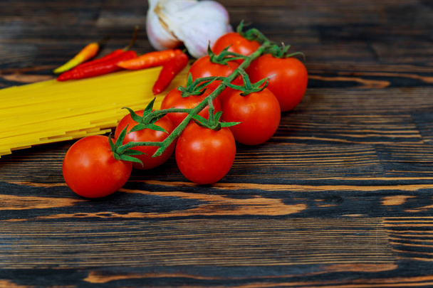 Pohled shora rajčata, papriku, česnek a těstoviny ingredience pro přípravu italských těstovin. Čerstvé rajče pepř česnek a špagety na tmavé kamenné pozadí s kopií prostor. - Fotografie, Obrázek