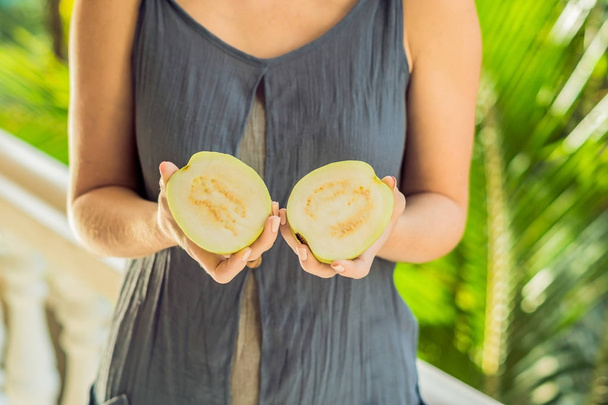 guava in beautiful female hands on a green background.. - Foto, immagini