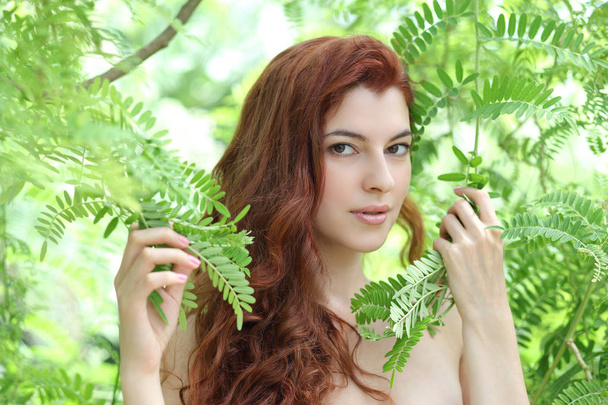 πορτρέτο του μια νεαρή όμορφη γυναίκα με πράσινα φύλλα - Φωτογραφία, εικόνα