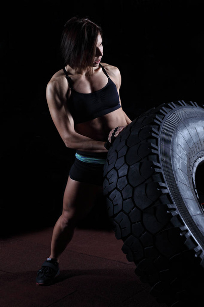 Fit und stark. fitte Frau kippt Reifen in der Turnhalle. - Foto, Bild