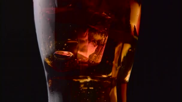 Fizzy pepsi with ice in a glass spray gases on a black background. Close up - Footage, Video