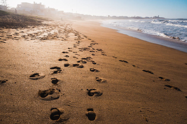 Schilderachtig uitzicht op een strand en de voet wordt afgedrukt op het zand  - Foto, afbeelding