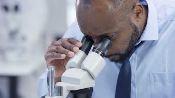 4K Close up of medical researcher in the lab looking at a slide under microscope - Video, Çekim
