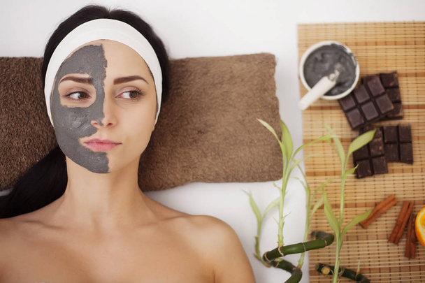 Спа-масаж для молодої жінки з маскою на обличчі - в приміщенні
 - Фото, зображення