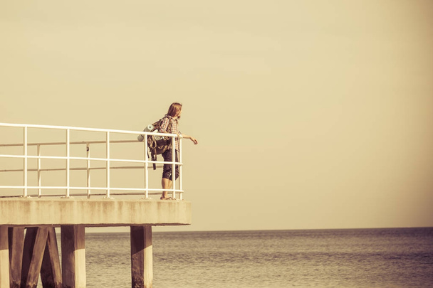 Man hiker with backpack on pier, sea landscape  - Photo, image