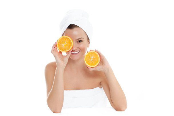 Beautiful young woman with clean fresh skin is holding two half oranges. Facial treatment - Fotografie, Obrázek