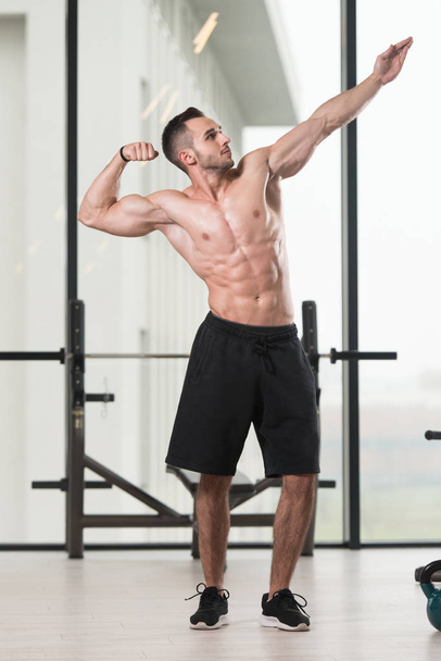 Portrait Of A Young Physically Fit Man Showing His Well Trained Body - Muscular Athletic Bodybuilder Fitness Model Posing After Exercises - Fotó, kép