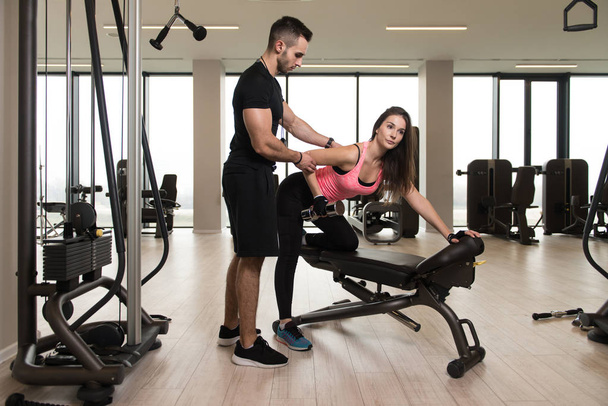 Personal Trainer Showing Young Woman How To Train Back On Bench In The Gym - Fotoğraf, Görsel