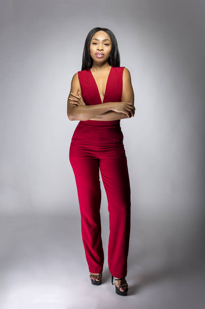 Black African female fashion model wearing red pantsuit for spring design.  The clothing looks semi formal or casual but elegant.  The image depits modern style trend. - Foto, immagini