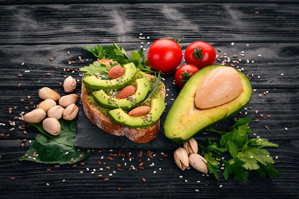 Sandwich with avocados and almonds. On a wooden background. Top view. Free space for your text. - Фото, зображення