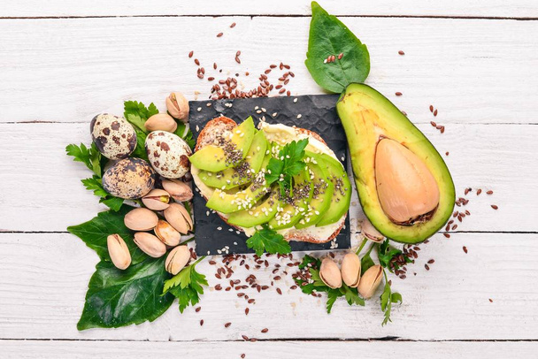 Sandwich with avocado, butter and chia seeds. On a wooden background. Top view. Free space for your text. - Zdjęcie, obraz