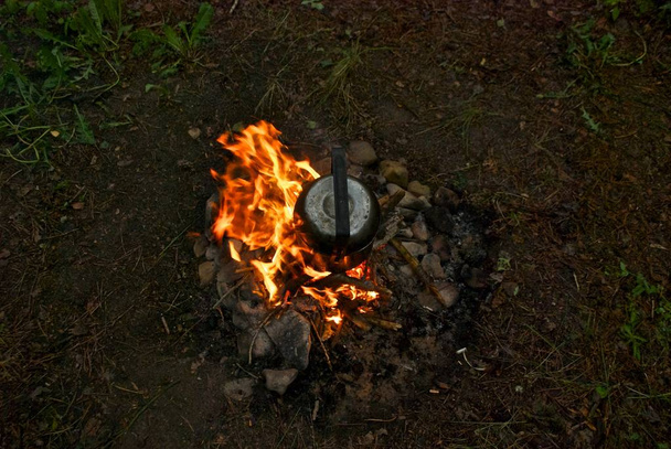 Vista superior de uma panela de alumínio em uma fogueira. Folhas soltas e pedras no chão. Camping viagem para a floresta
. - Foto, Imagem