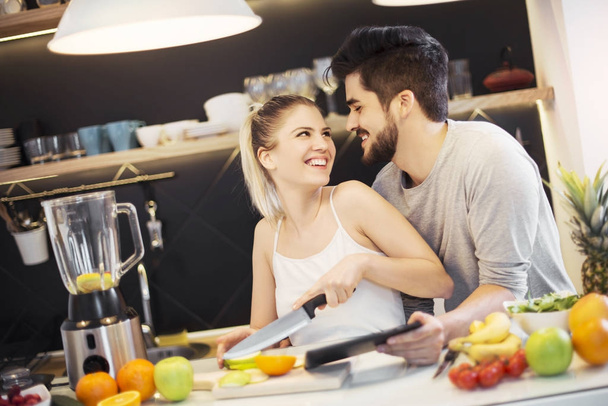 Young, romantic couple preparing food in the kitchen - Valokuva, kuva