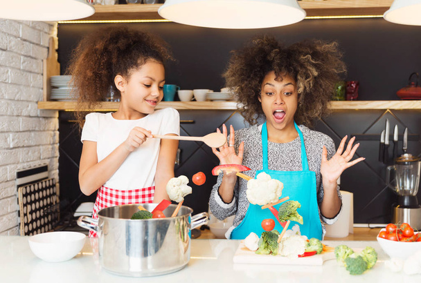 Beautiful African American woman and her daughter cooking in the kitchen - Valokuva, kuva