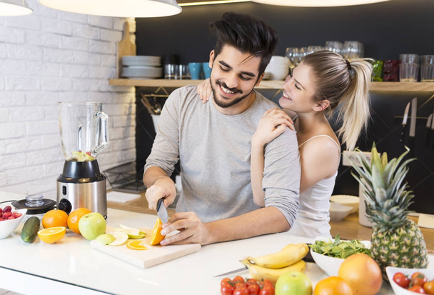 Young couple cutting fruit in the kitchen - Foto, Bild