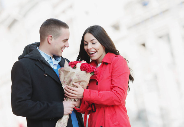 Man giving flowers bouquet to his girlfriend; Cute, young, romantic couple outdoors - Fotografie, Obrázek
