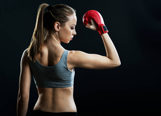 Fit, young woman boxer, black background - Fotó, kép