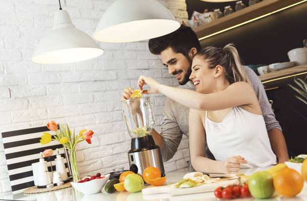 Young, romantic couple preparing food in the kitchen - Фото, зображення