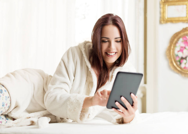 Beautiful woman using a tablet in a bright room - Zdjęcie, obraz