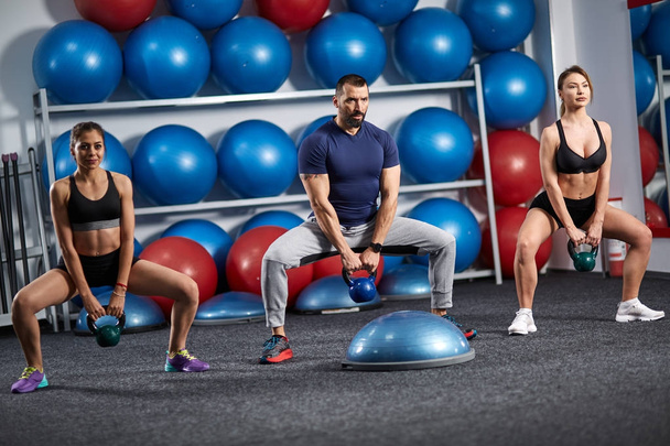 Fitness instructor with two girls working out with kettlebell - Valokuva, kuva
