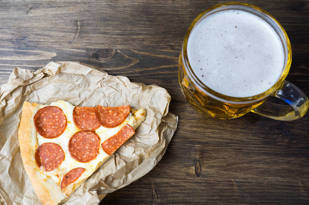 Light beer in glass and fragrant Italian pizza. - Photo, image