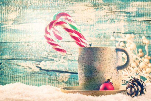 Christmas holiday background with cup of hot chocolate and candy canes over blue wood - Photo, Image