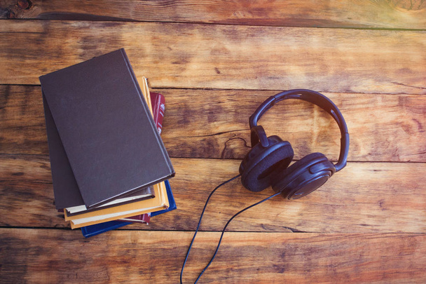 Sluchátka a hromadu knih o dřevěné pozadí. Audiobo - Fotografie, Obrázek