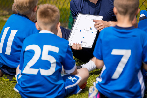 Coaching Kids Soccer. Football Team with Coach at the Stadium. Boys Listening to Coach's Instructions Before Competition. Coach Giving Team Talk Using Soccer Tactics Board - Photo, Image