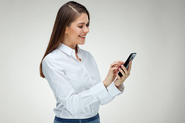 smiling happy businesswoman using smartphone on light background - Foto, afbeelding