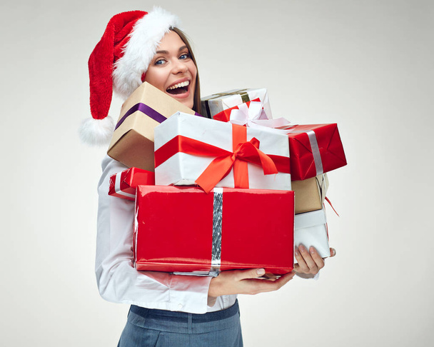 businesswoman wearing Santa hat holding pile of Christmas gift boxes  - Fotó, kép