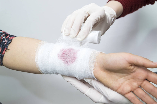 Bandaging a bleeding injury on the forearm using a white bandage - Photo, Image