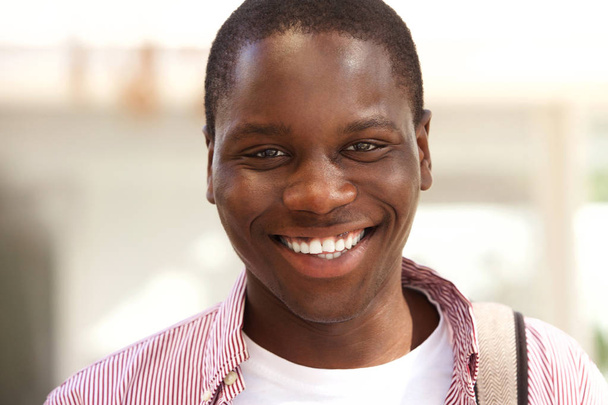 Primer plano retrato de feliz estudiante negro universitario sonriendo fuera
 - Foto, Imagen