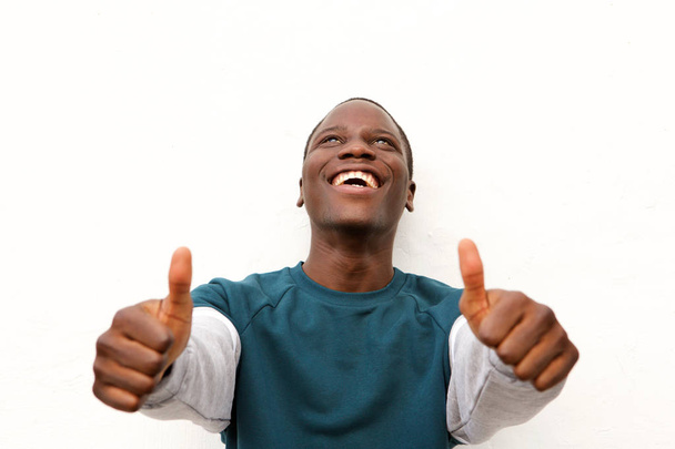 クローズ アップ ホワイト バック グラウンドに両手の親指を現して陽気な若いアフリカ男性の肖像画 - 写真・画像