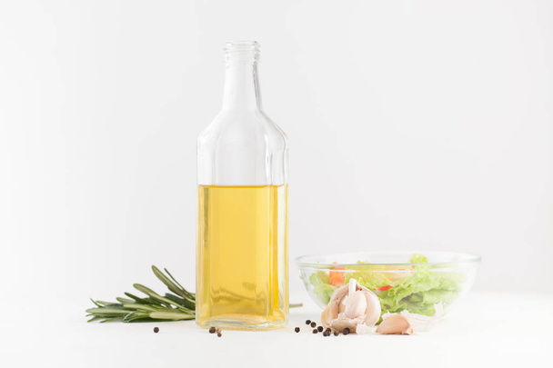 Oil in a bottle with spices and vegetable salad on white - Foto, Imagen