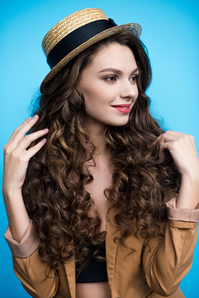 hosszú göndör hajú, canotier kalapot és kabátot vonzó fiatal nő - Fotó, kép