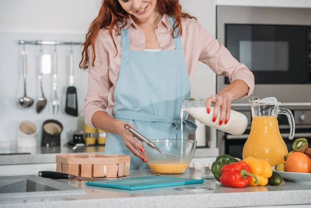cropped image of woman pouring milk in bowl to prepare batter - Photo, Image
